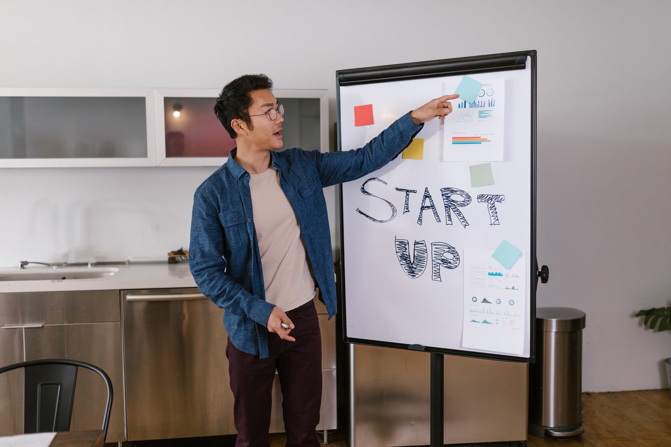 Man in Blue Shirt Pointing at Paper on White Board